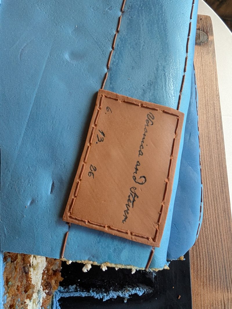 The fondant leather patch, hand-lettered with the couple's names and wedding date